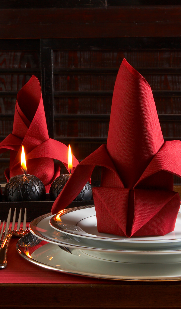 Красная салфетка на тарелке на столе с бокалами вина и свечами