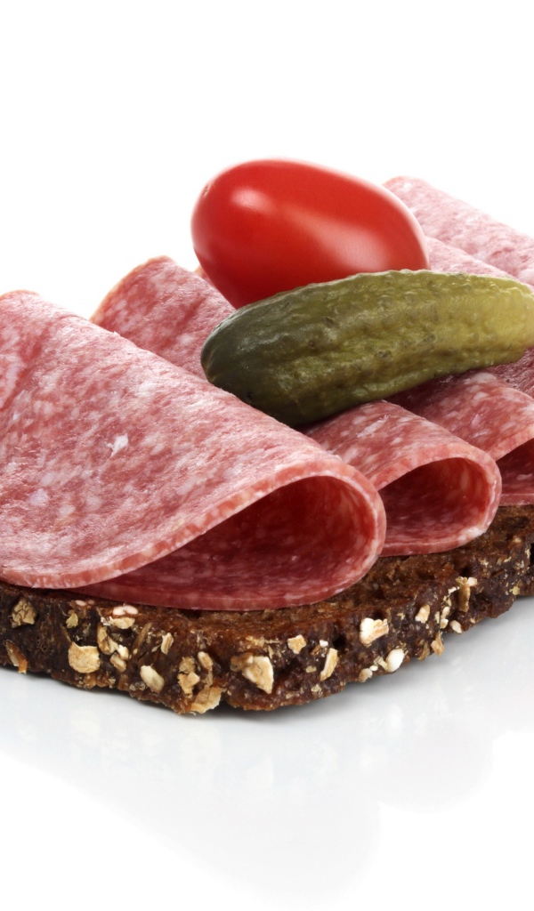 Бутерброд с черным хлебом, колбасой, соленым огурцом и помидором на белом фоне