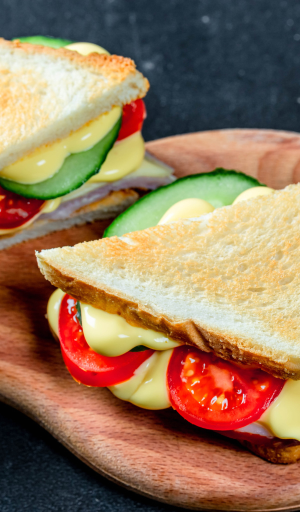 Сэндвич с сыром, помидорами и огурцами на столе