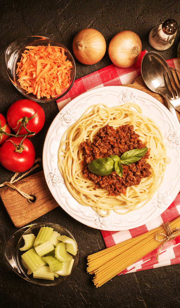 Спагетти с фаршем на столе с овощами