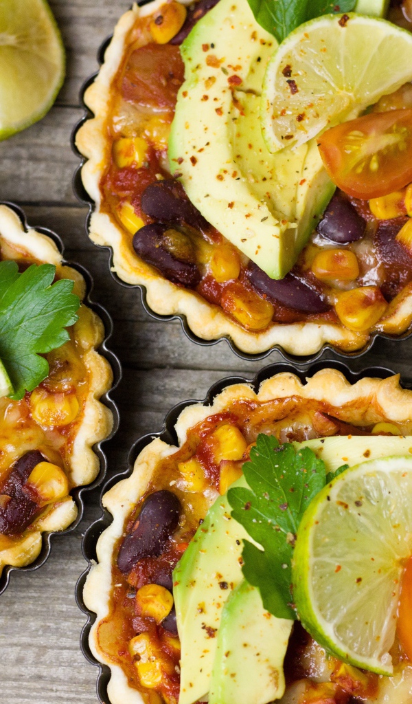 Тарталетки с блюдом, кусочками авокадо и лайма на столе