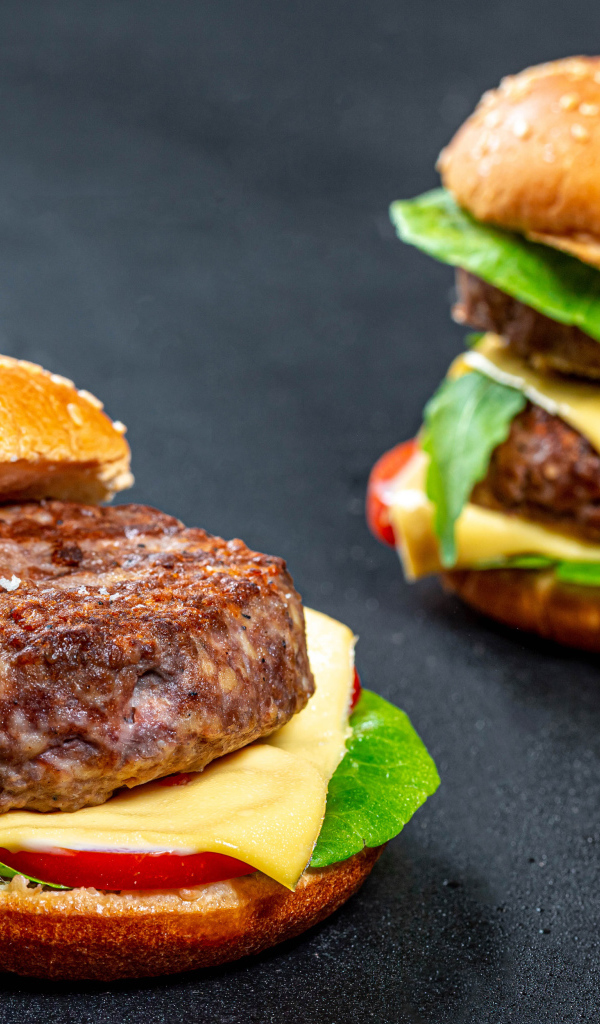 Два гамбургера с большой котлетой на столе