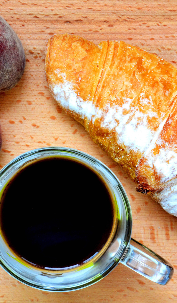 Два персика на столе с кофе и круассаном