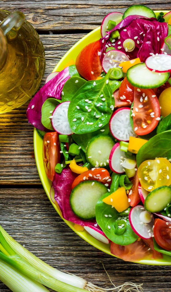 Овощной салат на столе с оливковым маслом и зеленым луком