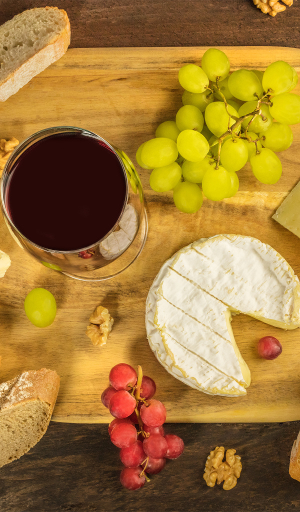 Вино, сыр, виноград и багет на столе 