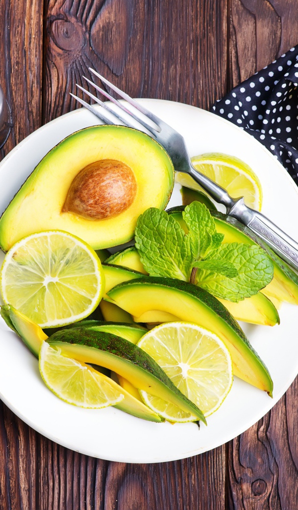 Авокадо и лимон нарезанный кусочками на тарелке