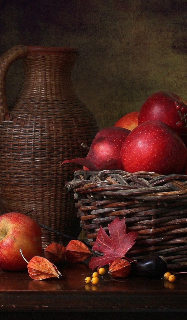 Корзина с красными яблоками на столе с кувшином 