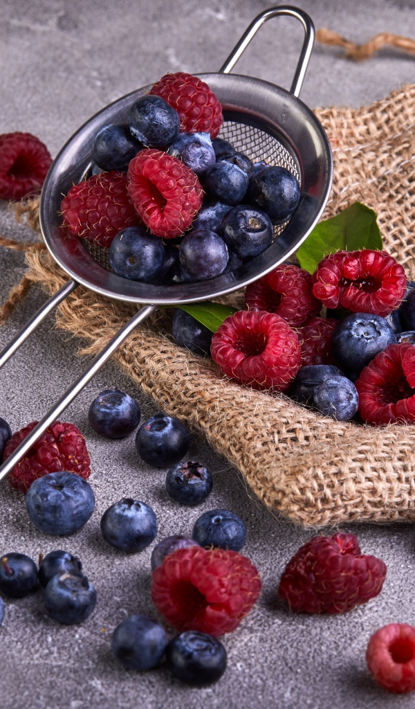 Ягоды черники и малины на столе с ситом