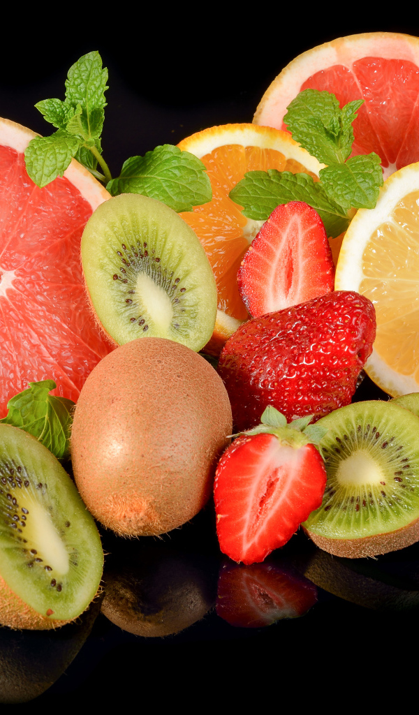 Цитрусовые фрукты на черном фоне с ягодами клубники 