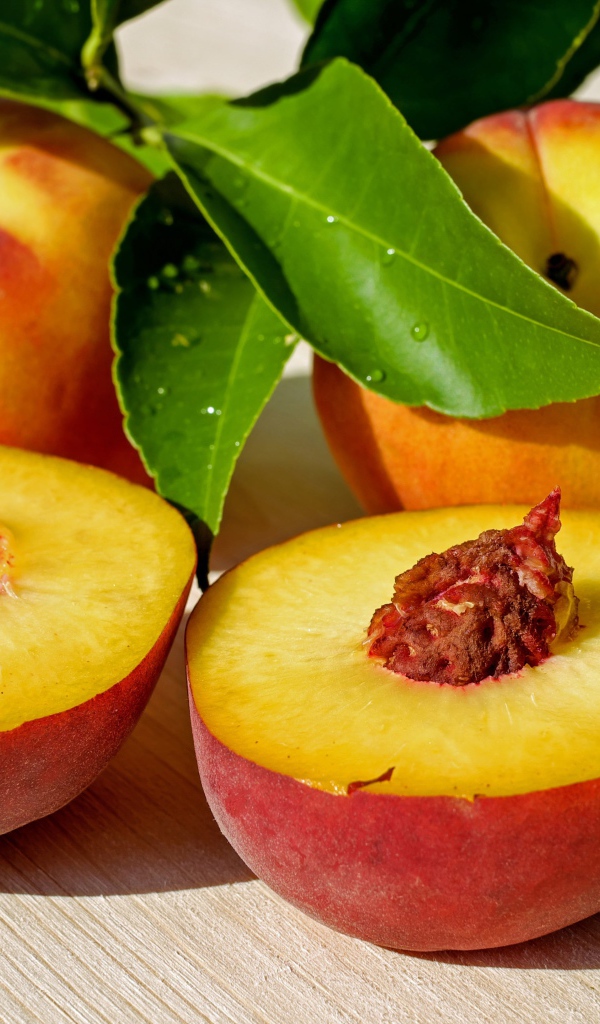 Сочные плоды нектарина с зелеными листьями на столе