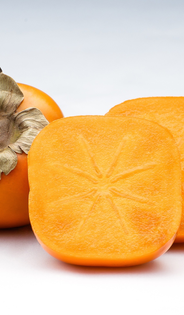 Оранжевая хурма на сером фоне крупным планом