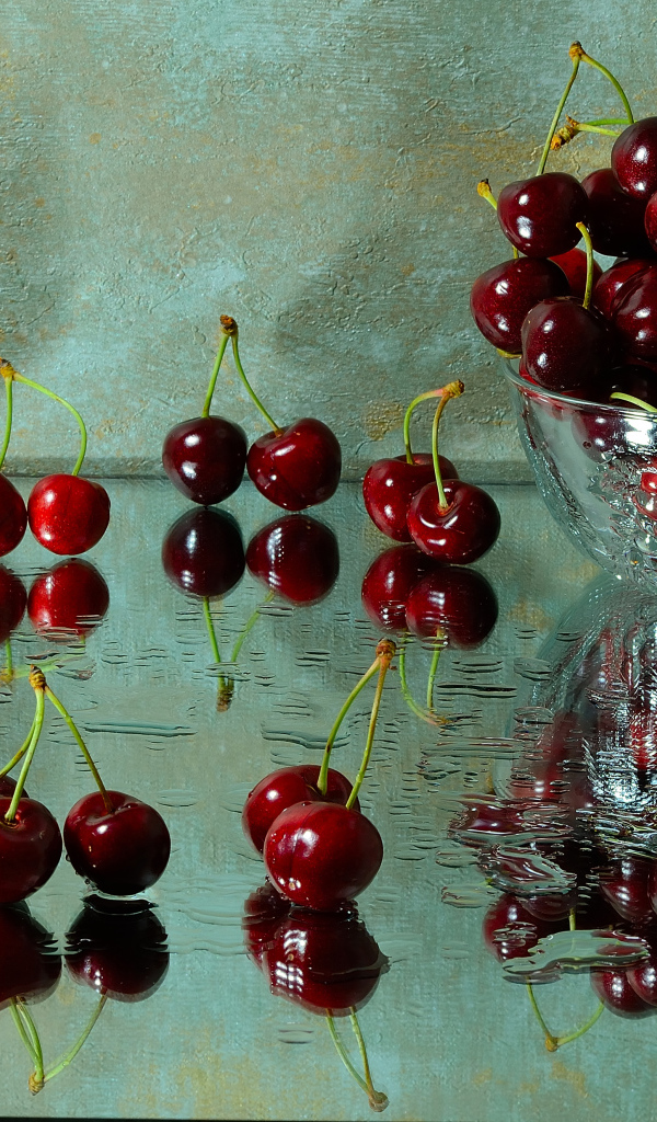 Спелые красные черешни отражаются в поверхности стола