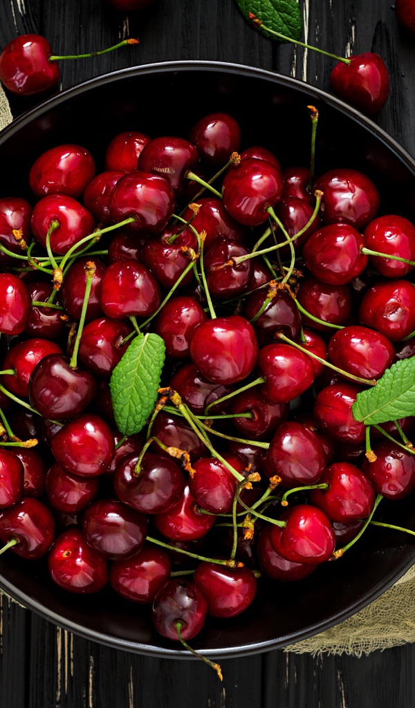 Спелые красные черешни в миске на столе
