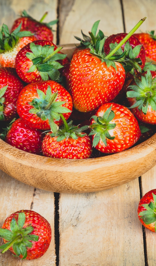 Спелая красная клубника в деревянной миске на столе