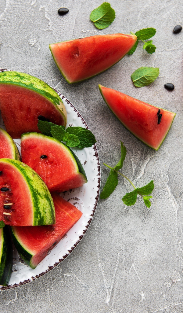 Полосатый арбуз нарезан кусочками на тарелке