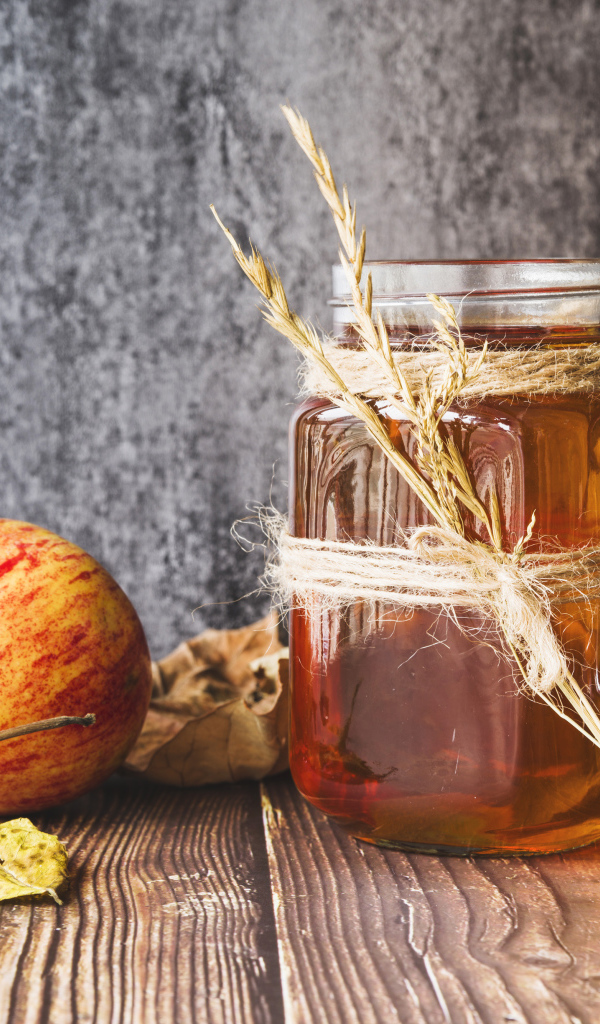 Три яблока с медом на столе на сером фоне