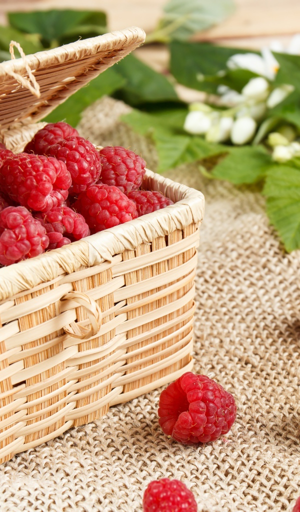 Плетеная корзина на столе с ягодами малины 