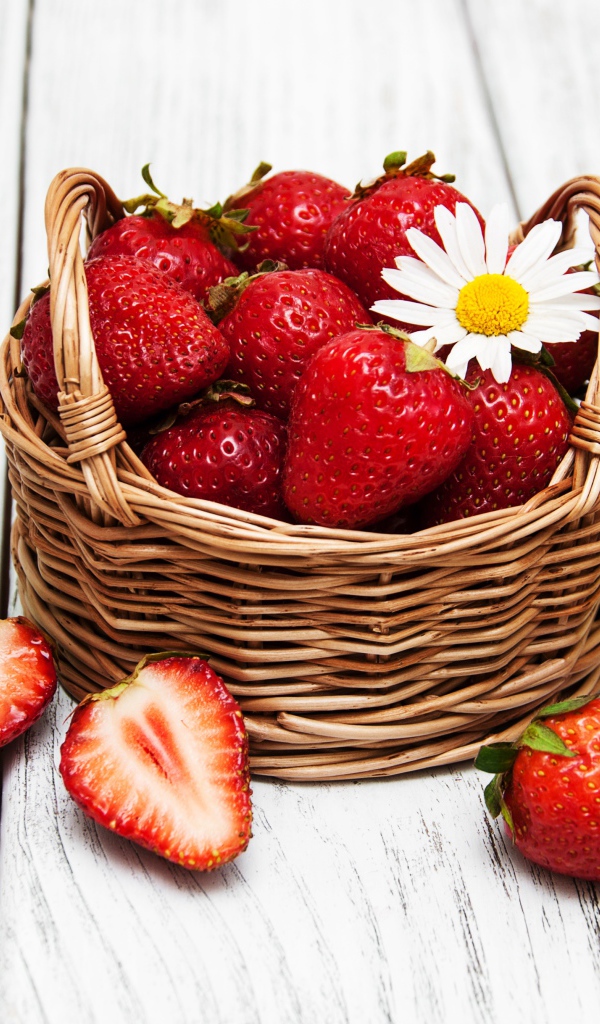 Плетеная корзинка с клубникой, ромашкой и зелеными листьями