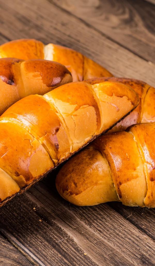 Аппетитные румяные круассаны на деревянном столе 