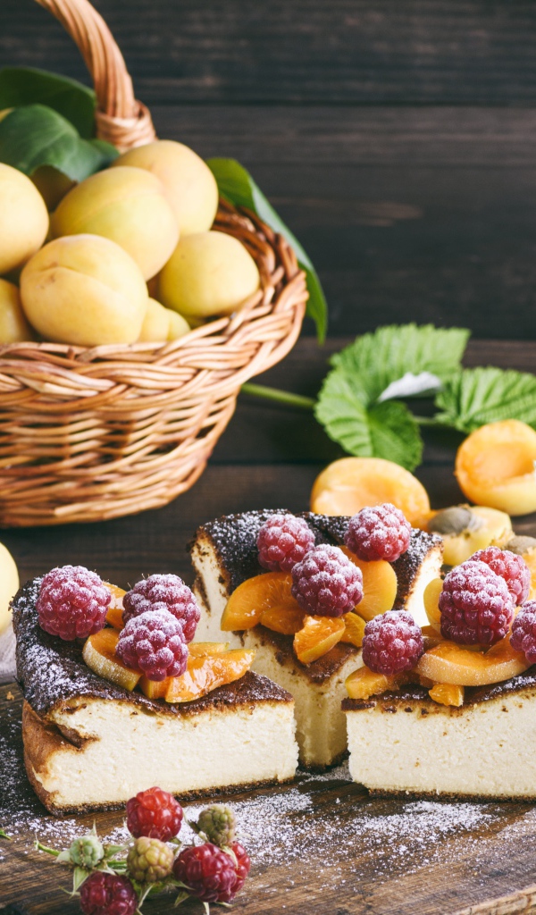 Вкусный фруктово - ягодный пирог на столе с корзиной с абрикосами