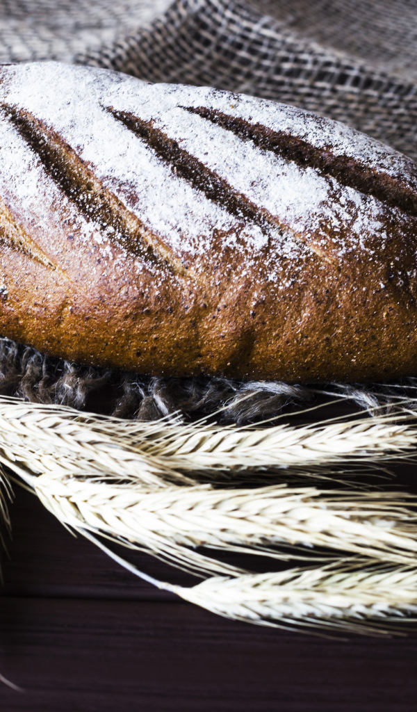 Буханка свежего хлеба на столе с колосьями пшеницы