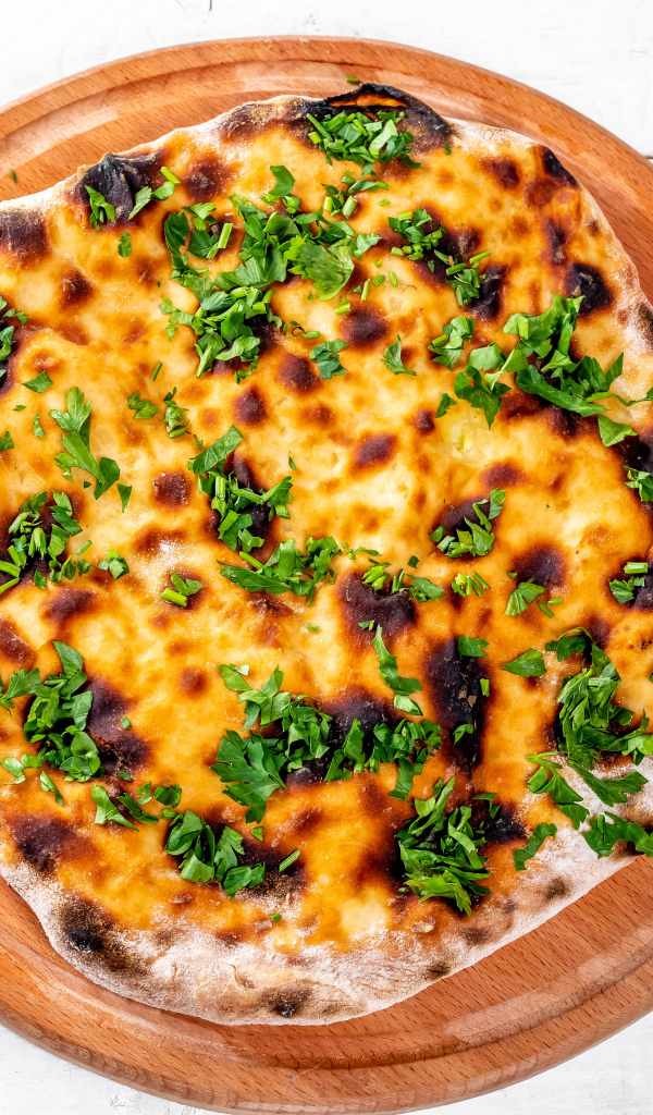 Пирог с сыром и зеленью на доске 