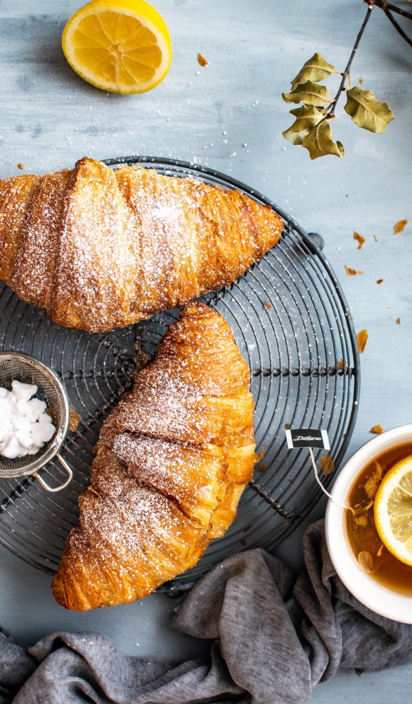 Два свежих круассана на столе с чаем