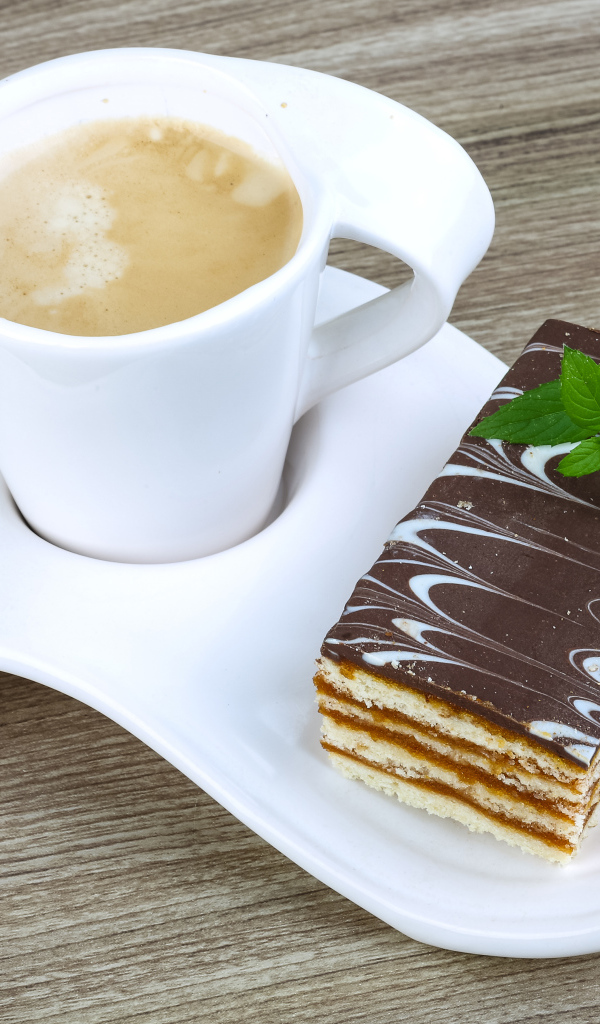 Чашка капучино на тарелке с пирожным 