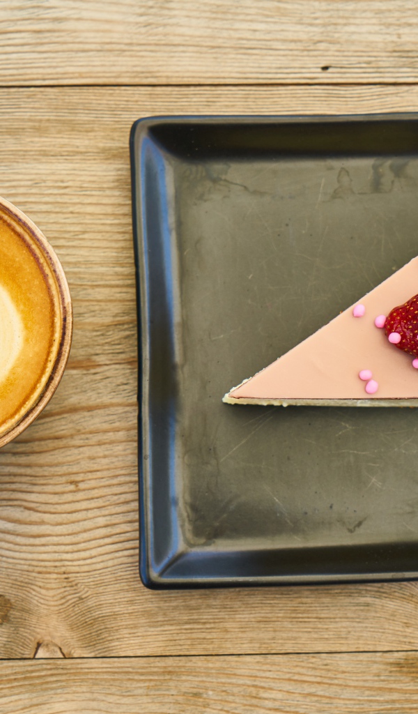 Кусок торта на черной тарелке с кофе