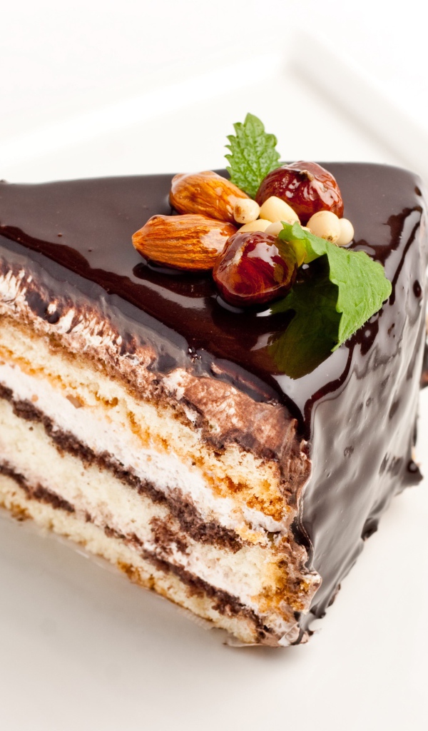 Кусок торта с шоколадом и орехами на белом фоне