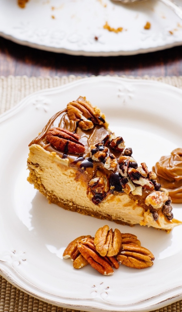 Кусок торта с орехами на белой тарелке на столе с кофе