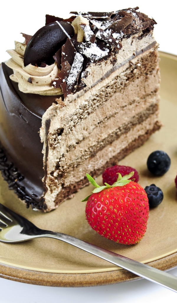 Кусок торта с кремом на тарелке с ягодами и вилкой