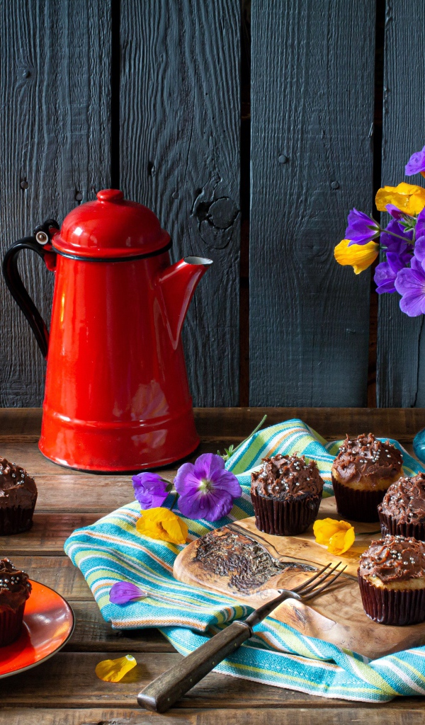 Аппетитные свежие кексы с кремом на столе с кофе, лампой и букетом цветов