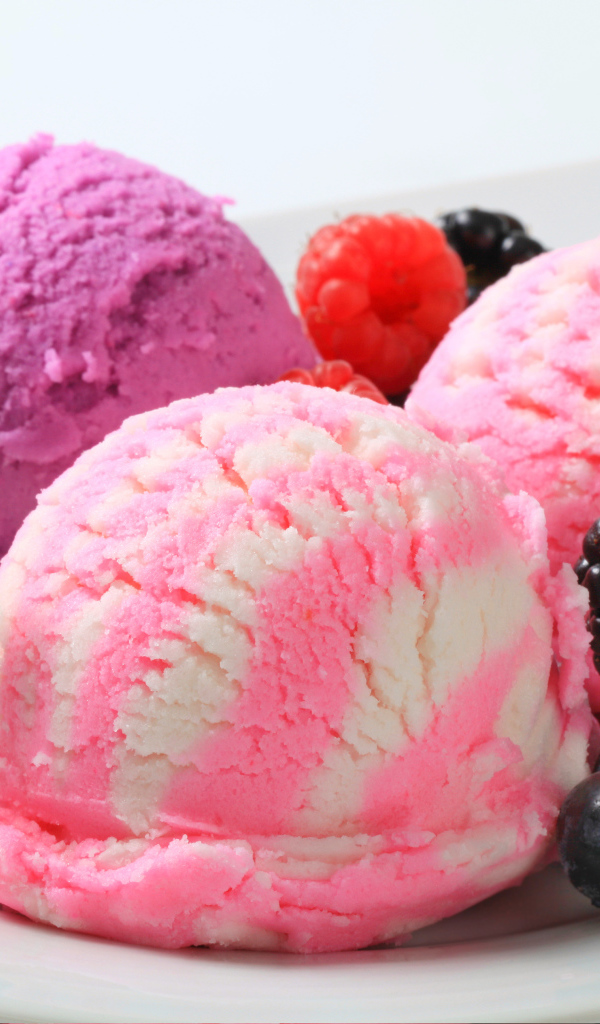 Шарики фруктового мороженого на белой тарелке с ягодами