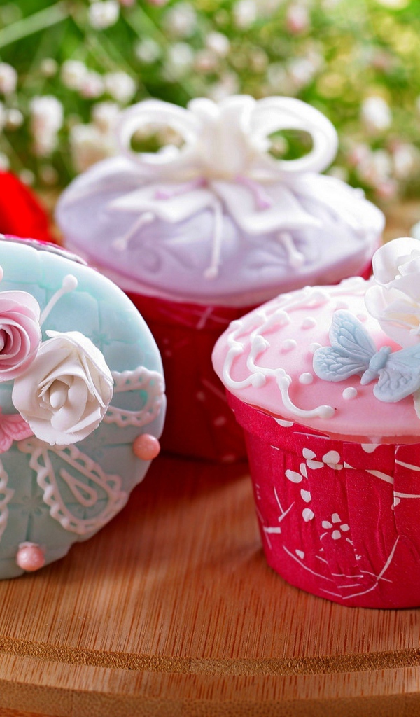 Красиво украшенные кексы на доске с цветами