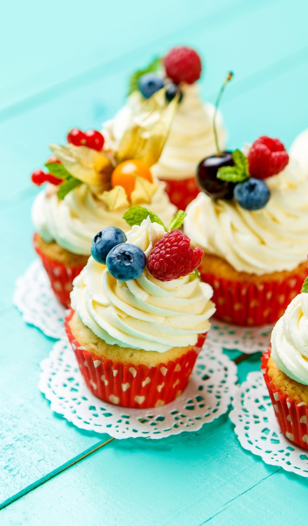 Кексы со взбитыми сливками украшены ягодами