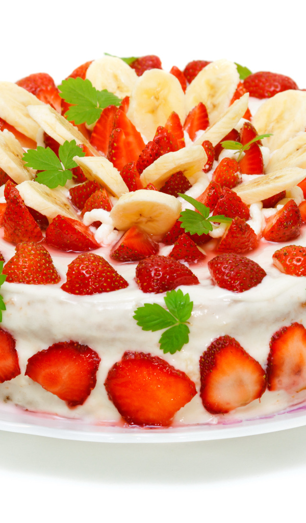 Большой торт с клубникой и бананами на белом фоне