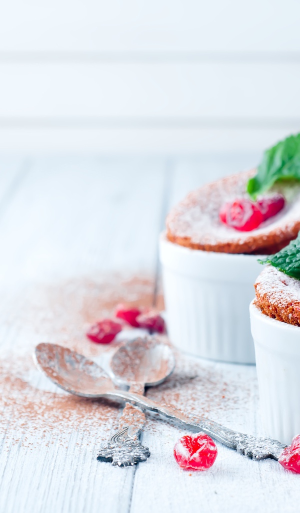 Пирожное с ягодами и сахарной пудрой на столе с ложками