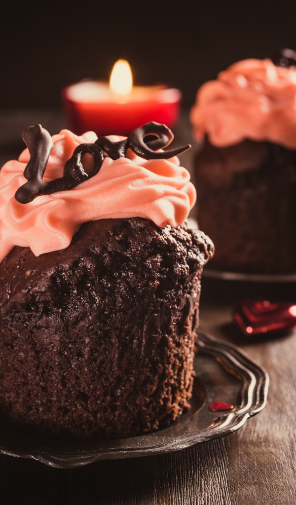 Шоколадные кексы с кремом на столе со свечами и розами