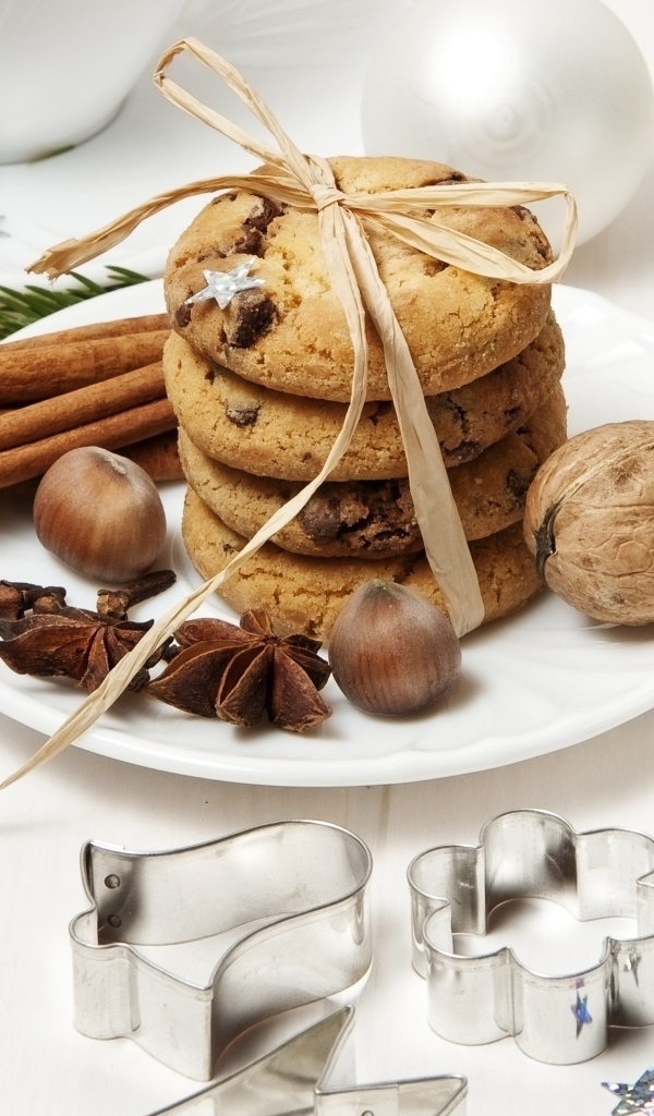 Печенье на тарелке с орехами и корицей на столе с игрушками 