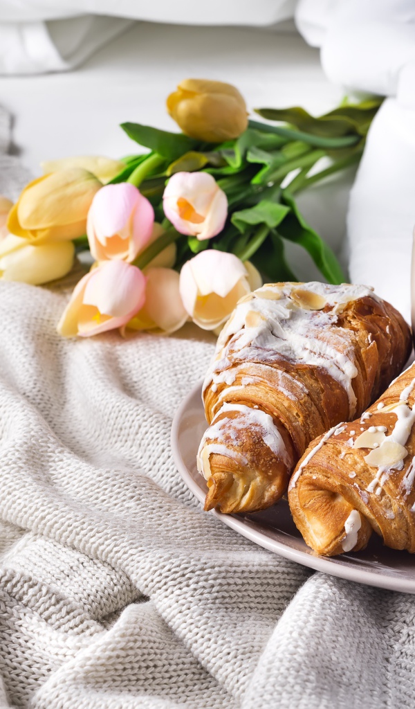 Круассаны на кровати с кофе и букетом тюльпанов