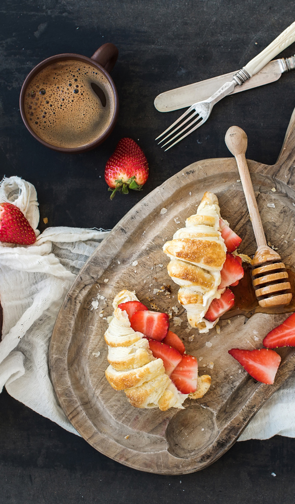 Круассаны на доске с клубникой и медом