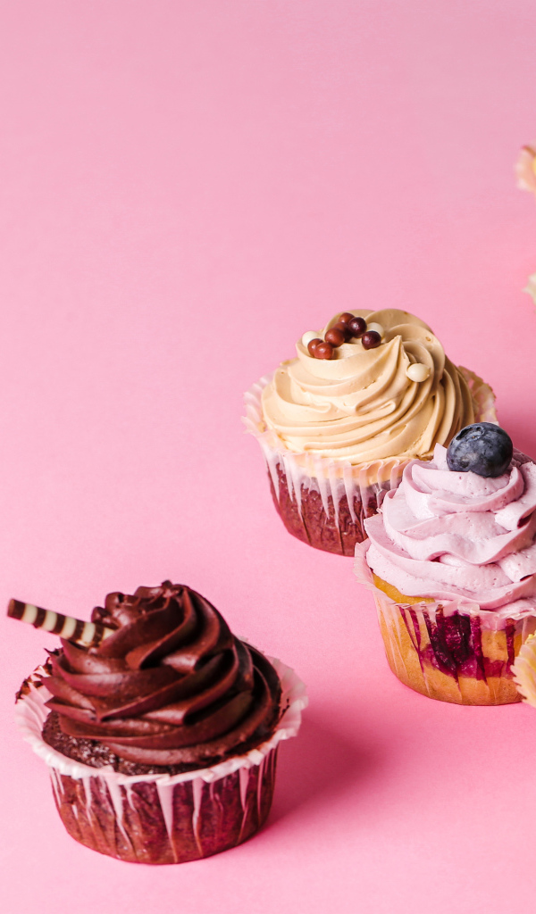 Кексы с разноцветным кремом на розовом фоне