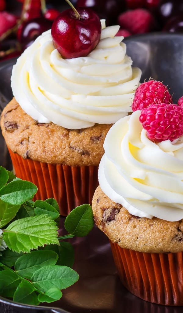 Аппетитные кексы с кремом и ягодами на блюде