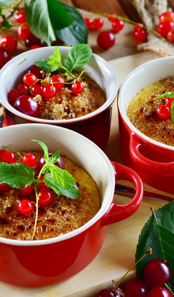 Десерт в красной посуде на столе с вишней и красной смородиной