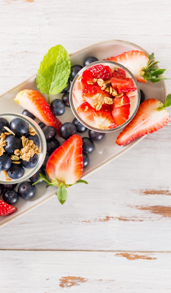 Десерт с ягодами черники и клубники на деревянном столе