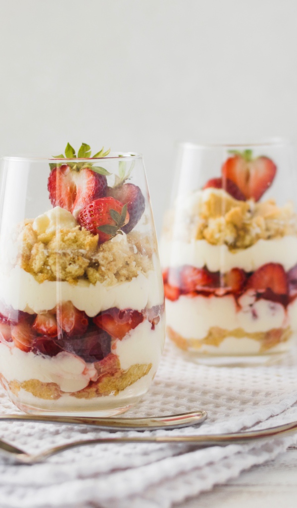 Десерт с клубникой в стеклянных стаканах на столе 