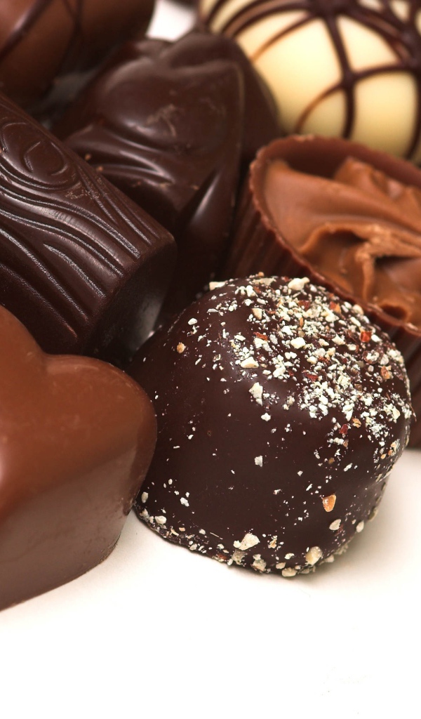 Разные шоколадные конфеты на белом фоне 