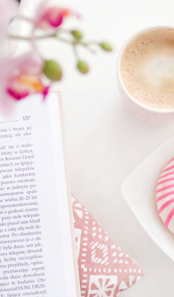 Пончик с чашкой кофе на столе с книгой