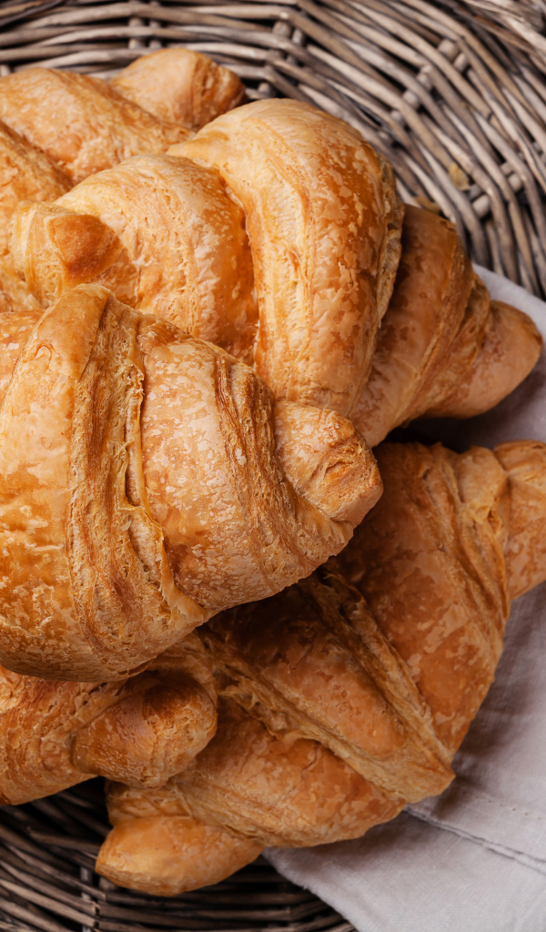 Свежие круассаны в корзинке с полотенцем